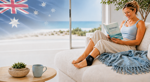 Woman reading a book on a couch with an Australian flag in the background